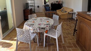 Ein geräumiger Wohnbereich mit einem runden Tisch, weißen Stühlen, einer Couch und einem Fernseher.