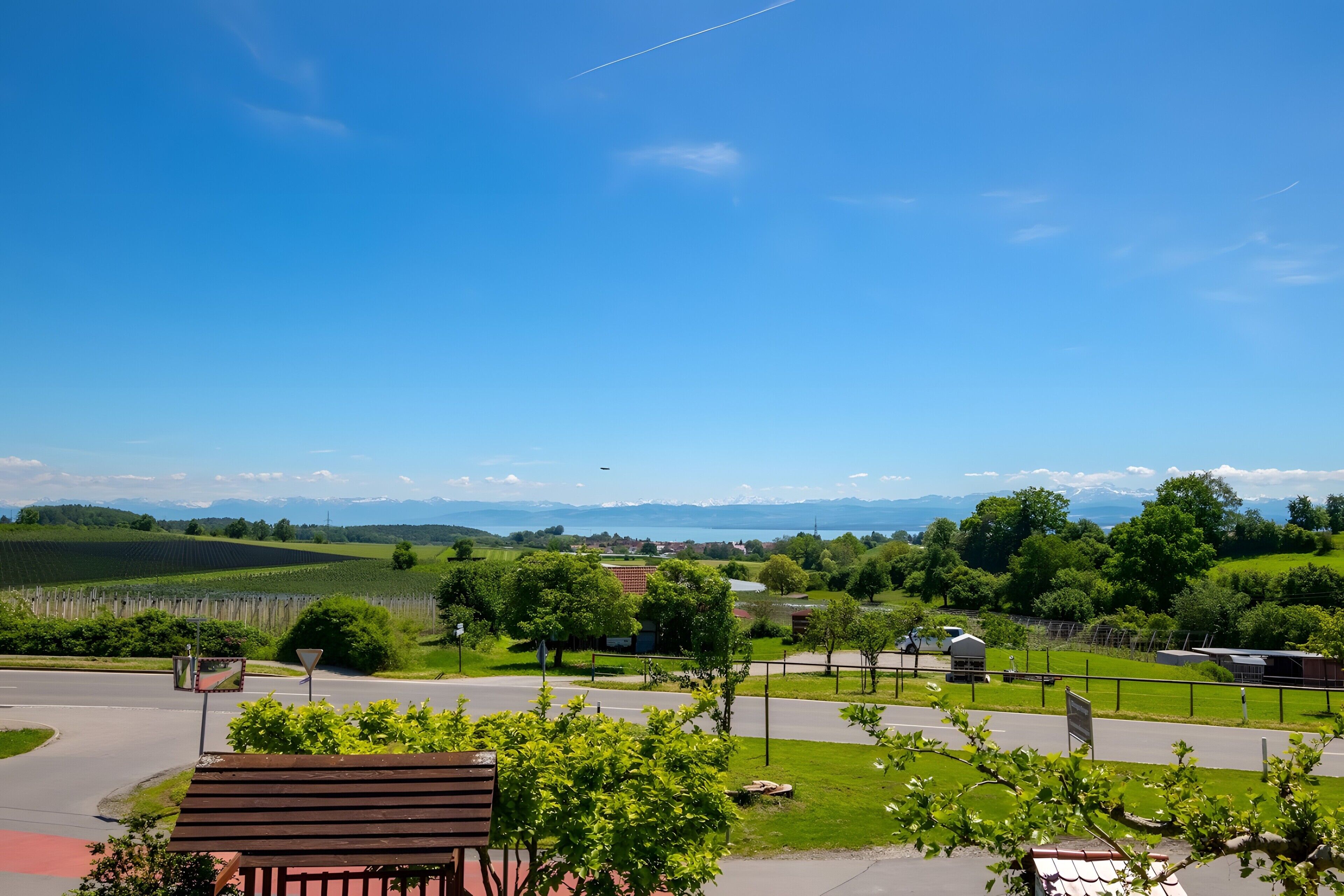 Ländliche Landschaft mit einer Straße, einer Bank und einer entfernten Bergblick.