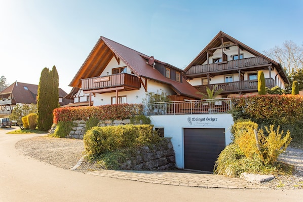 Ein zweistöckiges Gebäude mit einem Schild, auf dem 'Weingut Geiger' steht.