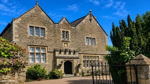A stone building with a gated entrance, multiple windows, and a brick pathway leading to the door. - Standard Double Room (Banbury)