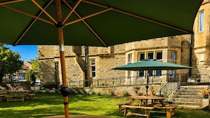 A stone building with a stone staircase, wooden picnic tables, and a green umbrella. - Standard Double Room (Banbury)