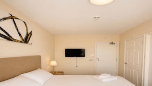 A hotel room with a bed, a flat-screen TV, a ceiling light, a door, and a wall-mounted artwork. - Standard Double Room (Banbury)