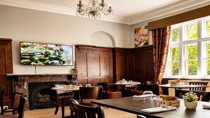 A dining room with a fireplace, wooden furniture, and a large window with curtains. - Standard Double Room (Banbury)