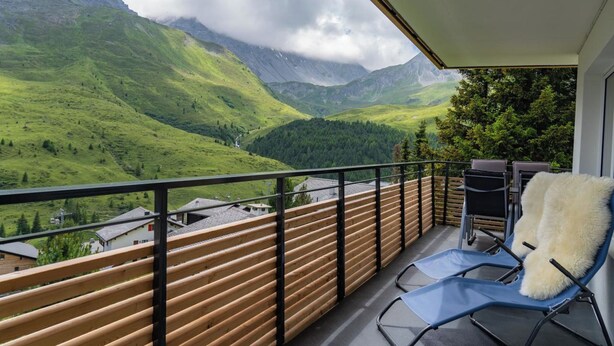 Een balkon met uitzicht op groene bergen en een vallei.