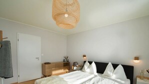 Een slaapkamer met een bed, nachtkastje, lamp, kledingkast en hanglamp.
