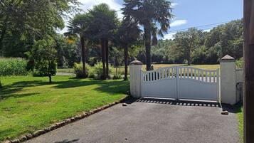 A gated entrance with a paved driveway leading to a property surrounded by greenery and trees.