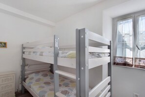 Ein Stockbett mit einem Fenster zur Rechten.