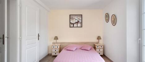 Un dormitorio con cama, mesitas de noche, una lámpara colgante y decoración en la pared.
