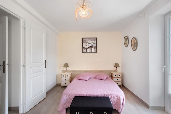 A bedroom with a bed, bedside tables, a hanging light fixture, and wall art.