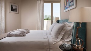 Hotellihuone, jossa on sänky, ikkuna verhoilla, taulu seinällä ja lamppu.