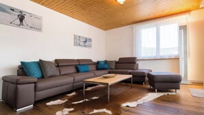 Un salon moderne avec un canapé d’angle en cuir marron, une table basse en bois et un tapis en peau de vache.