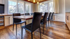 Un espace de restauration moderne avec un plafond en bois, de grandes fenêtres et des chaises noires.