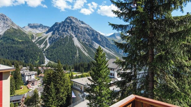 Une vue sur une montagne, avec une route, des bâtiments et des arbres.