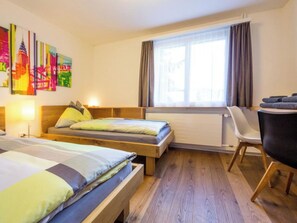 A hotel room with two beds, a desk, and a chair. - Les Chamois Appartement/Fewo,  , 8-Bettwohnung 8-Bettwohnung by Interhome (Arosa)