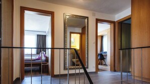 Une chambre d’hôtel avec un escalier en bois, un grand miroir et un lit recouvert d’un jeté violet.