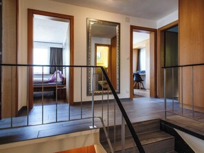 Ein Hotelzimmer mit einer Holztreppe, einem großen Spiegel und einem Bett mit lila Dekowaffe.