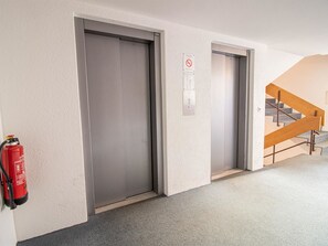 A hallway with two elevator doors, a fire extinguisher, and a staircase. - Rothornblick 46 by Arosa Holiday Appartement/Fewo,   Rothornblick 46 by Interhome (Arosa)