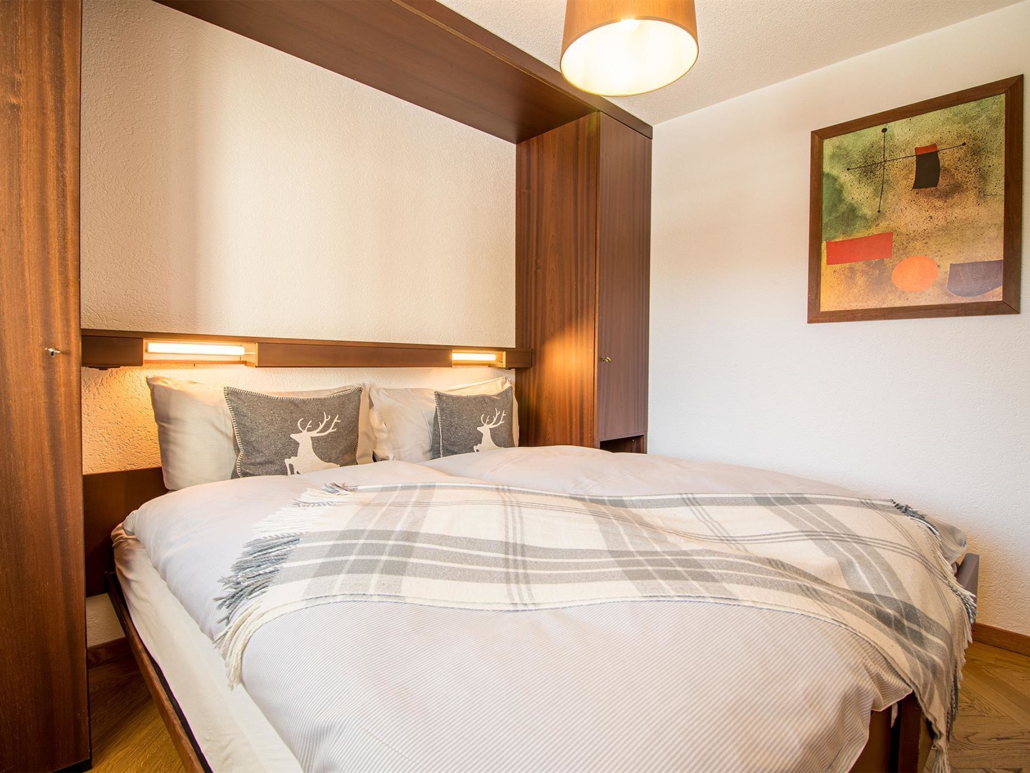 Quarto de hotel com cama, cabeceira e um quadro na parede.