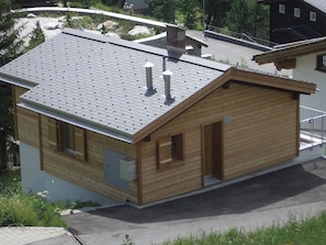 A wooden cabin with a sloped roof, a small attached shed, and a paved driveway. - Chalet Höckli 1 Appartement/Fewo,  , 6-Bettwohnung 6-Bettwohnung by Interhome (Arosa)