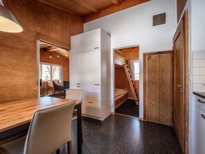 Una habitación pequeña con una mesa de madera, una silla, una cama y un armario.