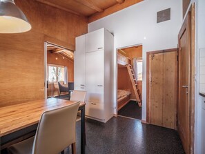 A compact room with a wooden table, chairs, a bed, and a wardrobe. - Chalet Höckli 1 Appartement/Fewo,  , 6-Bettwohnung 6-Bettwohnung by Interhome (Arosa)