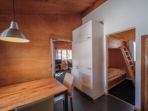 A compact room with a wooden table, a single chair, a wardrobe, and a bunk bed with a ladder. - Chalet Höckli 1 Appartement/Fewo,  , 6-Bettwohnung 6-Bettwohnung by Interhome (Arosa)