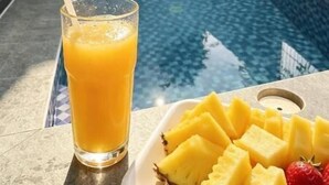 A swimming pool with a glass of orange juice and pineapple slices on a tray. - dParis Villas Ubud (Bali)