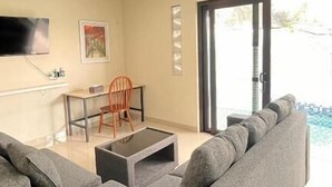 A living room with a sofa, coffee table, TV, and a dining area with chairs and a table. - dParis Villas Ubud (Bali)