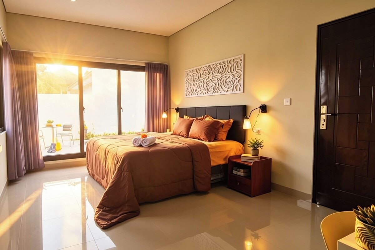 Un dormitorio con cama, mesita de noche, luz empotrada en la pared, panel decorativo y puerta corredera a un balcón.