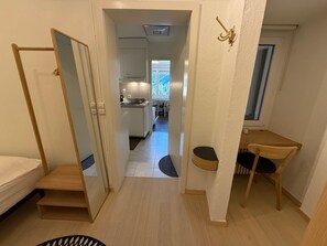 A narrow hallway leading to a kitchen and dining area with a window, a bed, and a small table. - Jäggi 35 by Arosa Holiday Appartement/Fewo, Bad, WC, 1 Schlafraum by Interhome (Arosa)