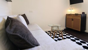 Ein modernes Wohnzimmer mit einer Couch, einem Glastisch, einem an der Wand befestigten Fernseher und einem Schrank mit Webmuster.