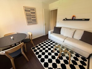 A living room with a round table, two chairs, a sofa, and a patterned rug. - Jäggi 35 by Arosa Holiday Appartement/Fewo, Bad, WC, 1 Schlafraum by Interhome (Arosa)