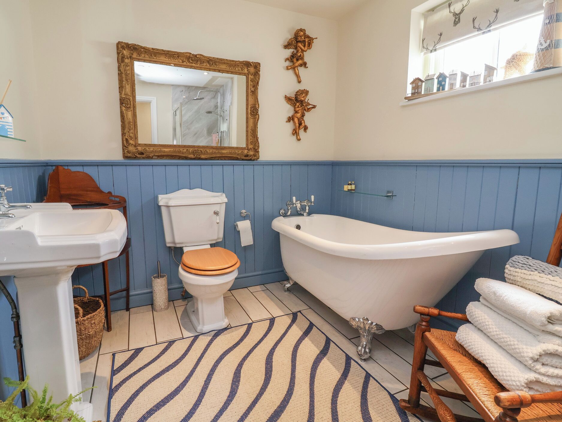 Un baño con un lavamanos blanco, un inodoro, una bañera y un felpudo azul a rayas.