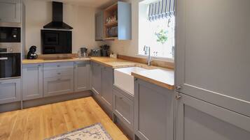 A modern kitchen with grey cabinets, a wooden countertop, and a built-in oven.