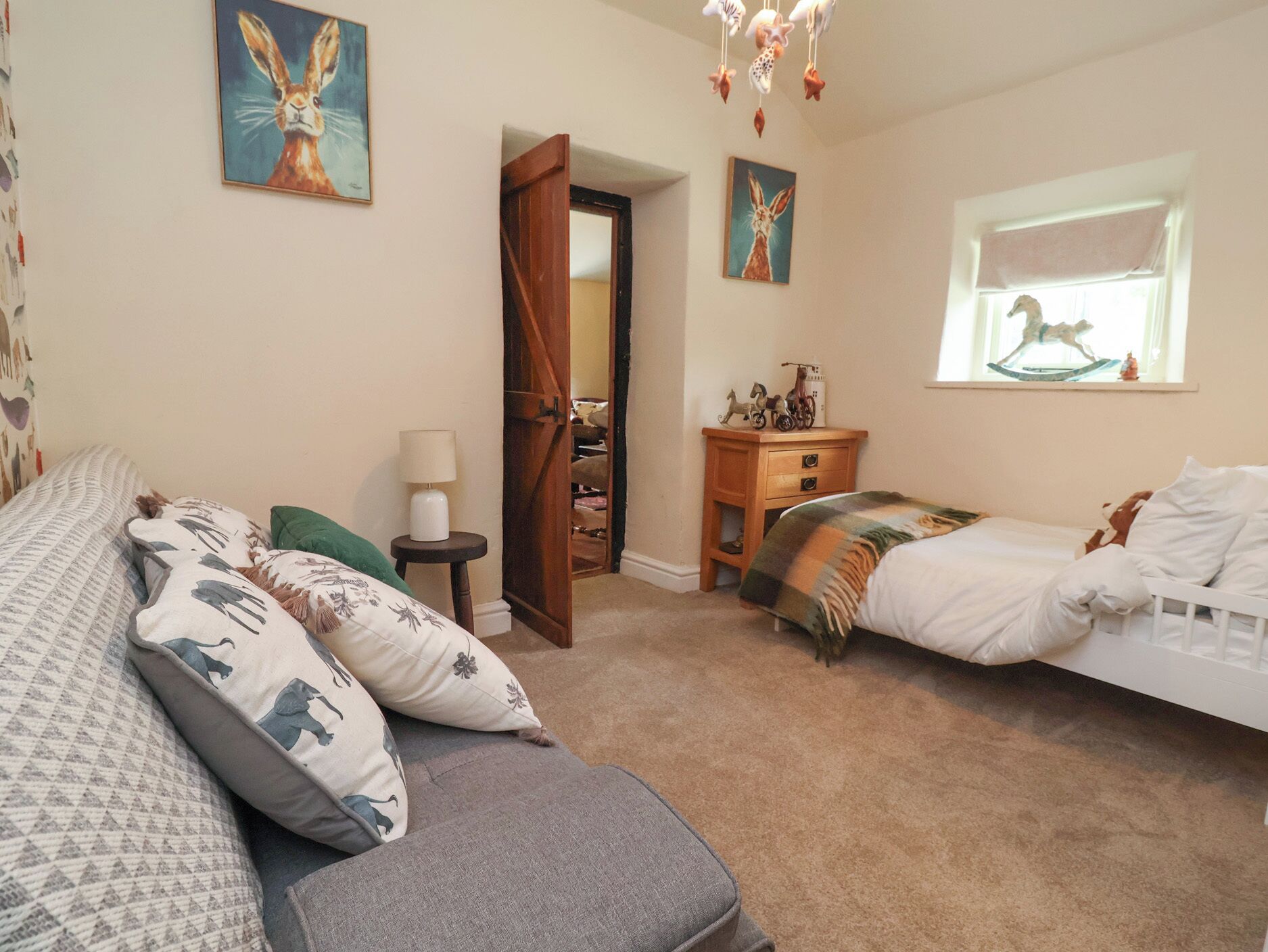 A bedroom with two beds, a dresser, a lamp, and artwork on the walls.