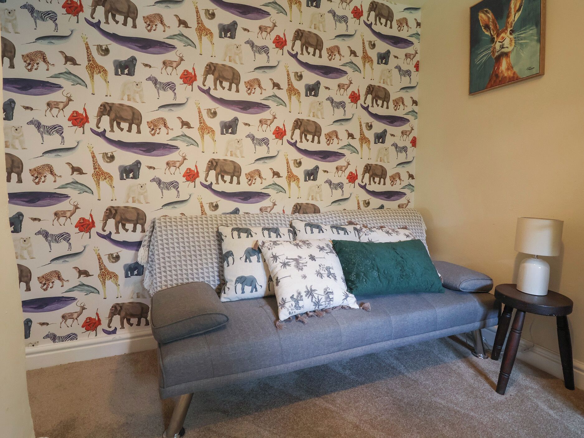 A living room with a sofa, pillows, a small table, and a lamp.