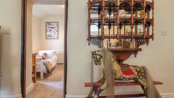 Quarto com um cavalinho de baloiço de madeira, um espelho e uma porta para outro espaço.