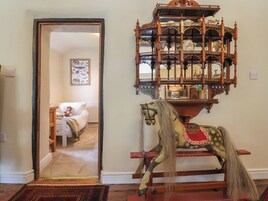 Una habitación con un caballo balancín de madera, un espejo y una puerta que da a otra habitación.