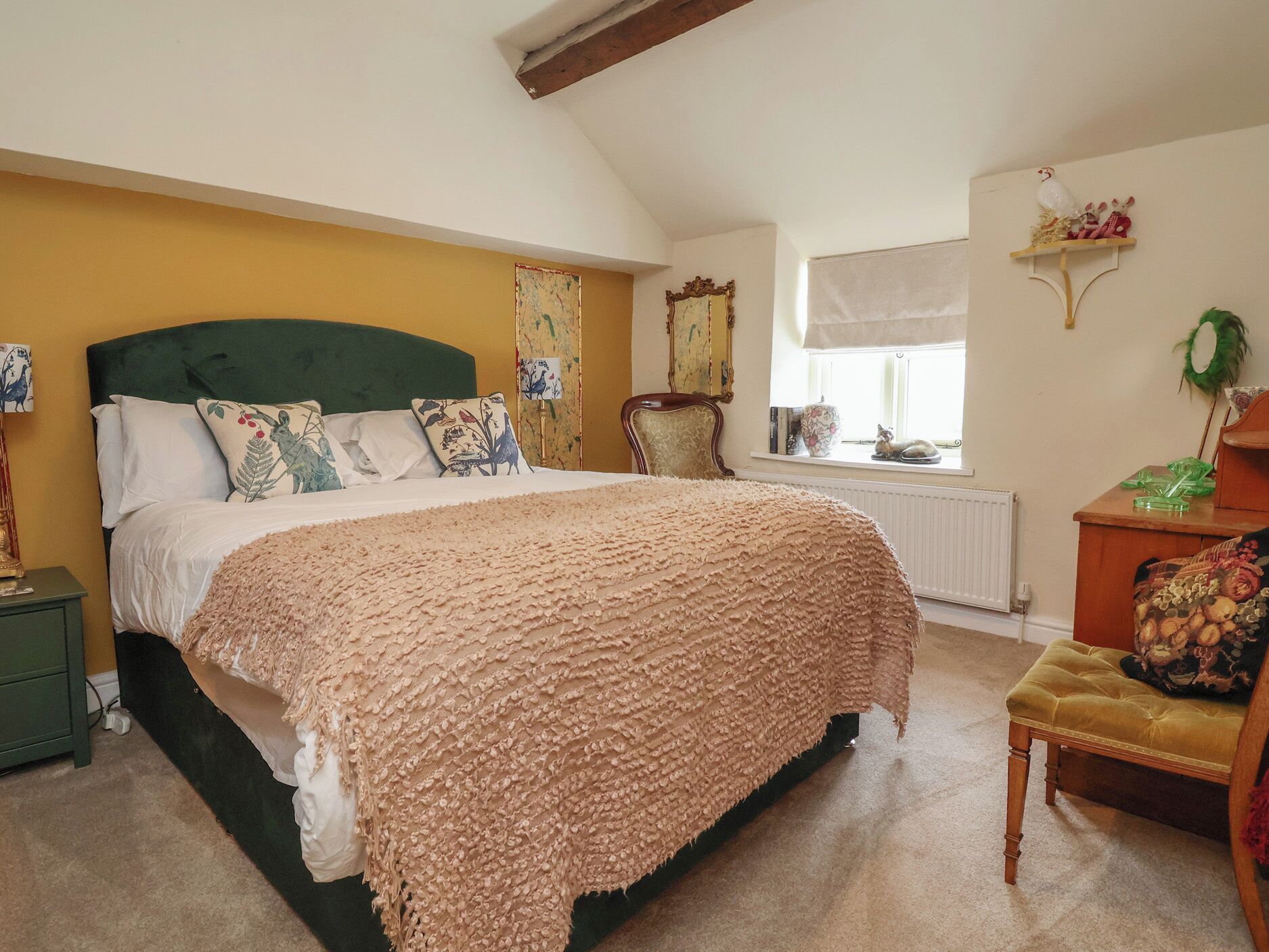Quarto com uma cama grande, uma cadeira, cômoda, janela e radiador.