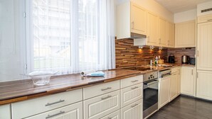 Une cuisine moderne avec des meubles blancs, un plan de travail en bois et un four encastré.