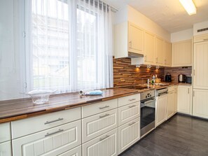 Eine moderne Küche mit weißen Schränken, einer Holz Arbeitsplatte und einem eingebauten Backofen.