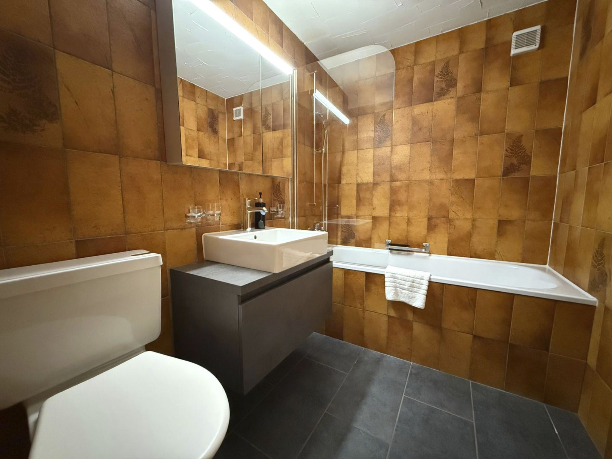 Een badkamer met toilet, wastafel en bad.