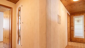 Un couloir doté de parquets en bois, d’un mur recouvert de miroirs et d’une porte ornée d’une fenêtre en forme de cœur.