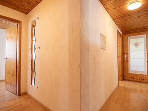 Ein Flur mit Holzböden, einer Spiegelwand und einer Tür mit einem herzförmigen Fenster.