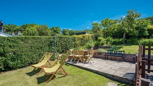 A patio with outdoor furniture, a hedge, and a brick wall. - Holiday Home With Sea Views In Llanfairfechan | Uwch-Y-Mor (Llanfairfechan)