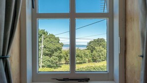 A window with a clear view of a landscape including trees and a body of water. - Holiday Home With Sea Views In Llanfairfechan | Uwch-Y-Mor (Llanfairfechan)