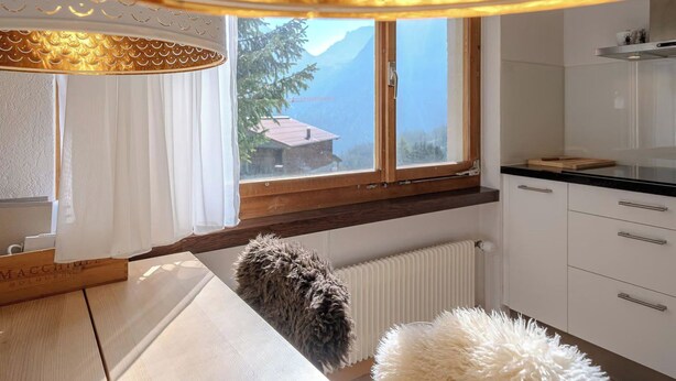 Eine moderne Küche mit einem großen Fenster, Holzschränken und einer weißen Arbeitsplatte.
