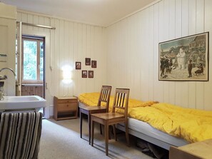 Une chambre à coucher comprenant un lit, deux chaises, une table de chevet, une commode, une fenêtre et un tableau accroché au mur.