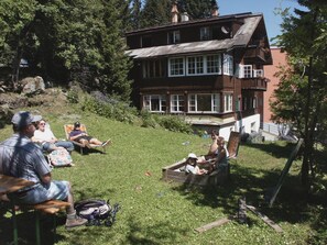 A large two-story house with a front porch, surrounded by a grassy yard and trees. - Chalet Willi-2.OG Appartement/Fewo, Dusche und Bad, WC, 6-Bettwohnung by Interhome (Arosa)