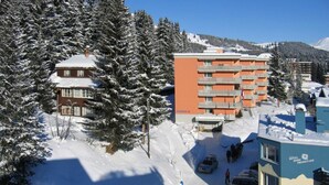 Ein Hotel mit mehreren Etagen, einem Parkplatz und verschneiter Umgebung.